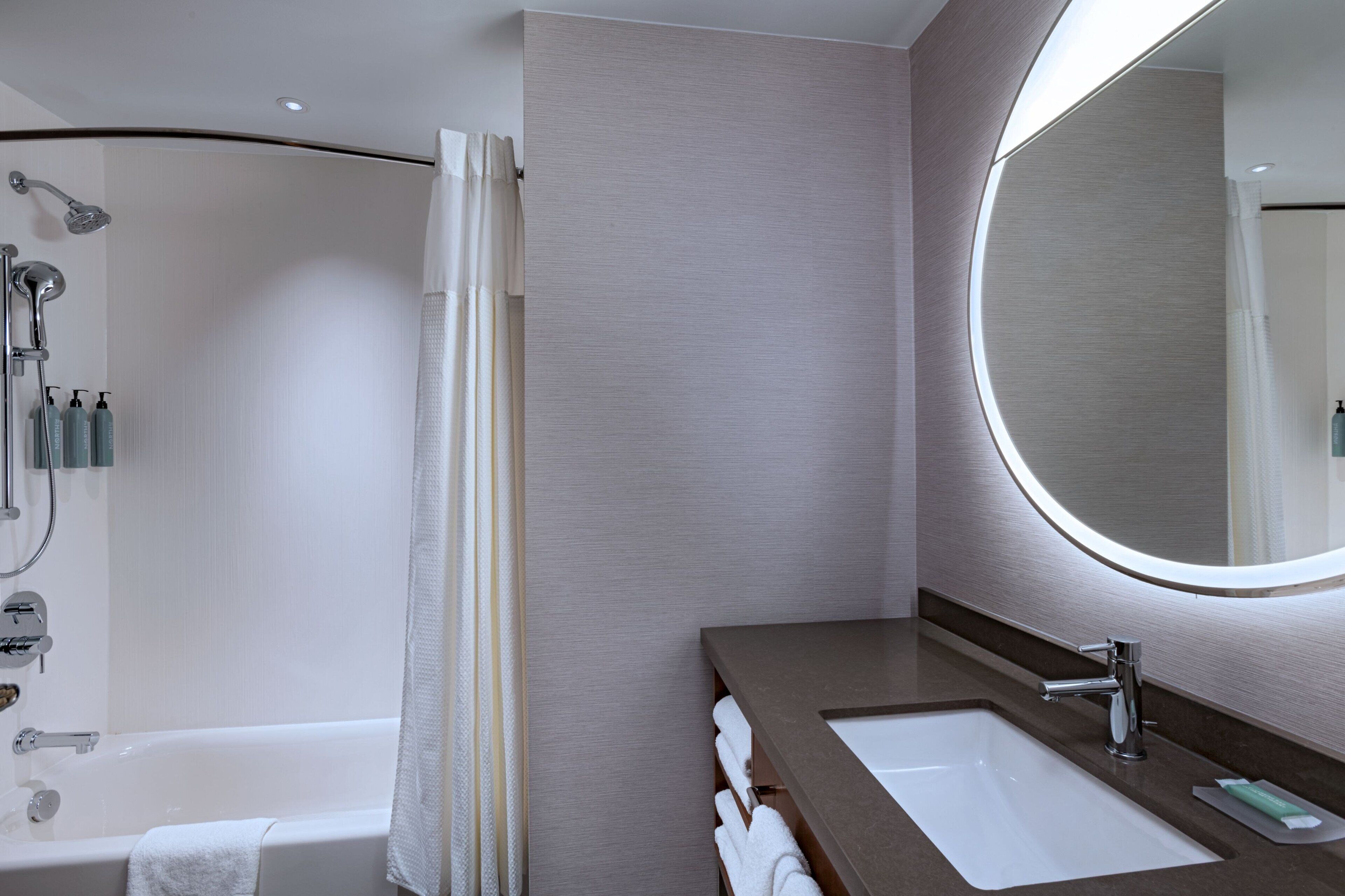 A modern bathroom with a bathtub, shower, and sink.