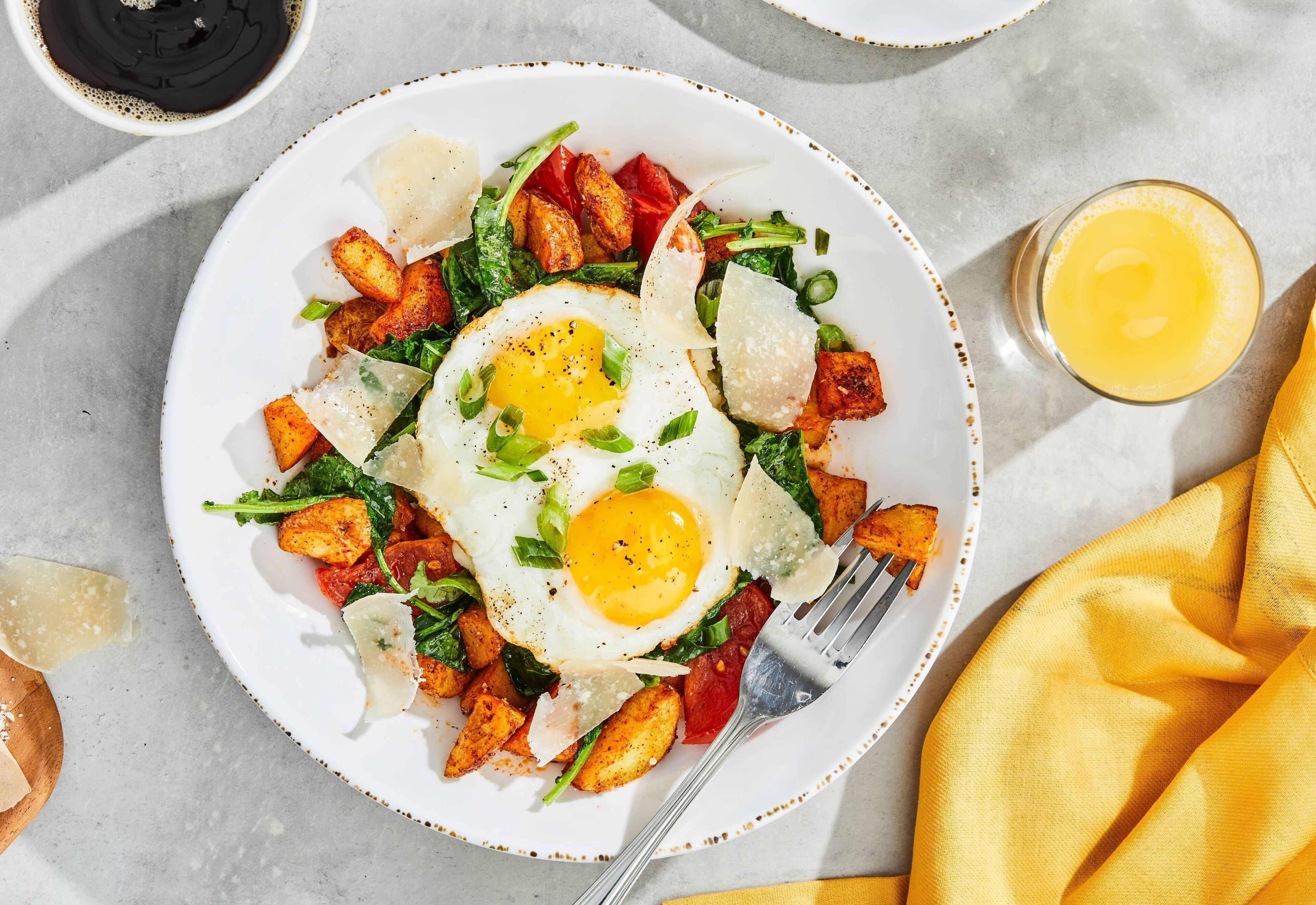 A plate of food with a fried egg, greens, and potatoes.