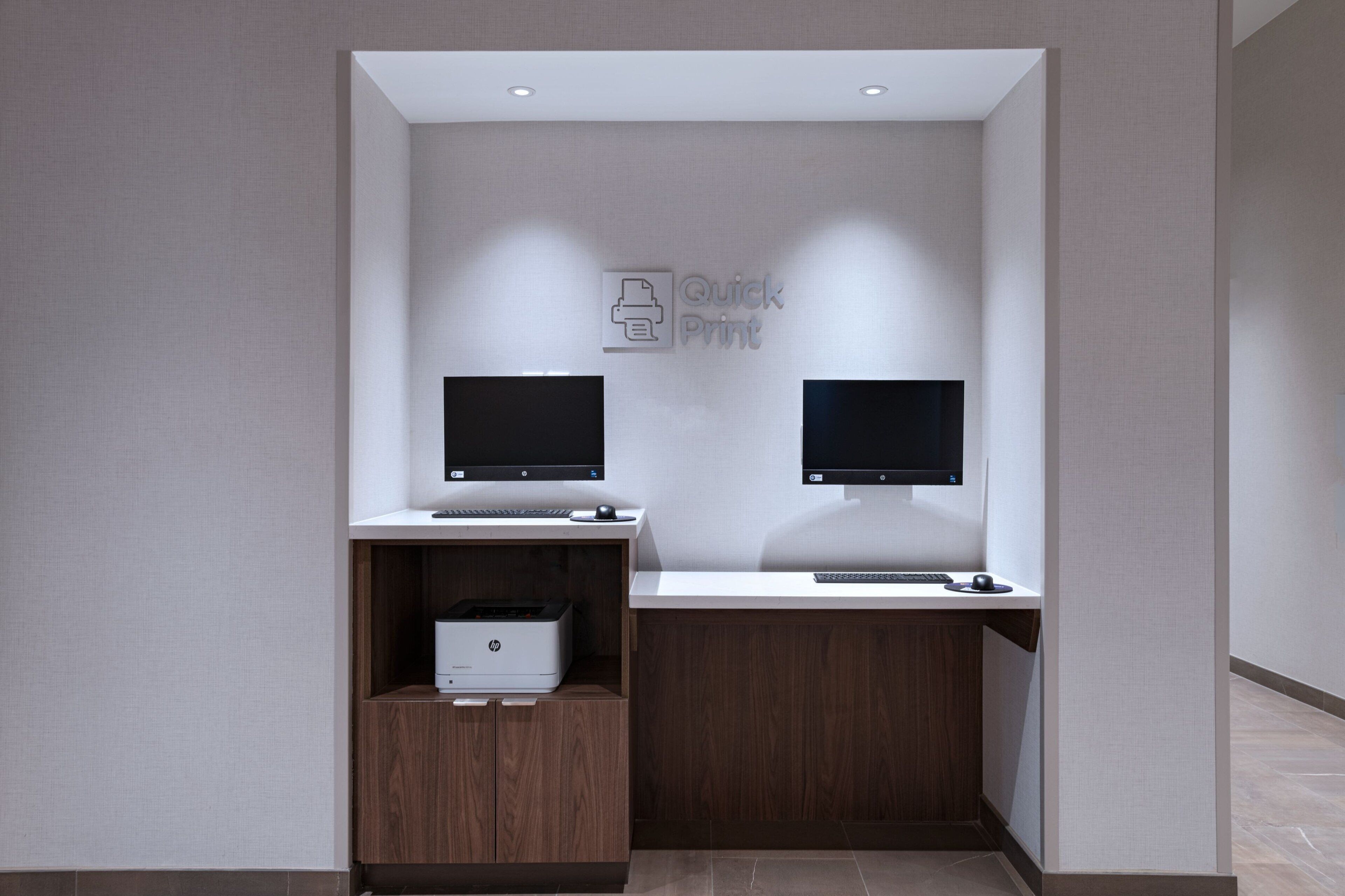 Um espaço de escritório moderno com duas mesas, cada uma equipada com um computador e uma impressora.