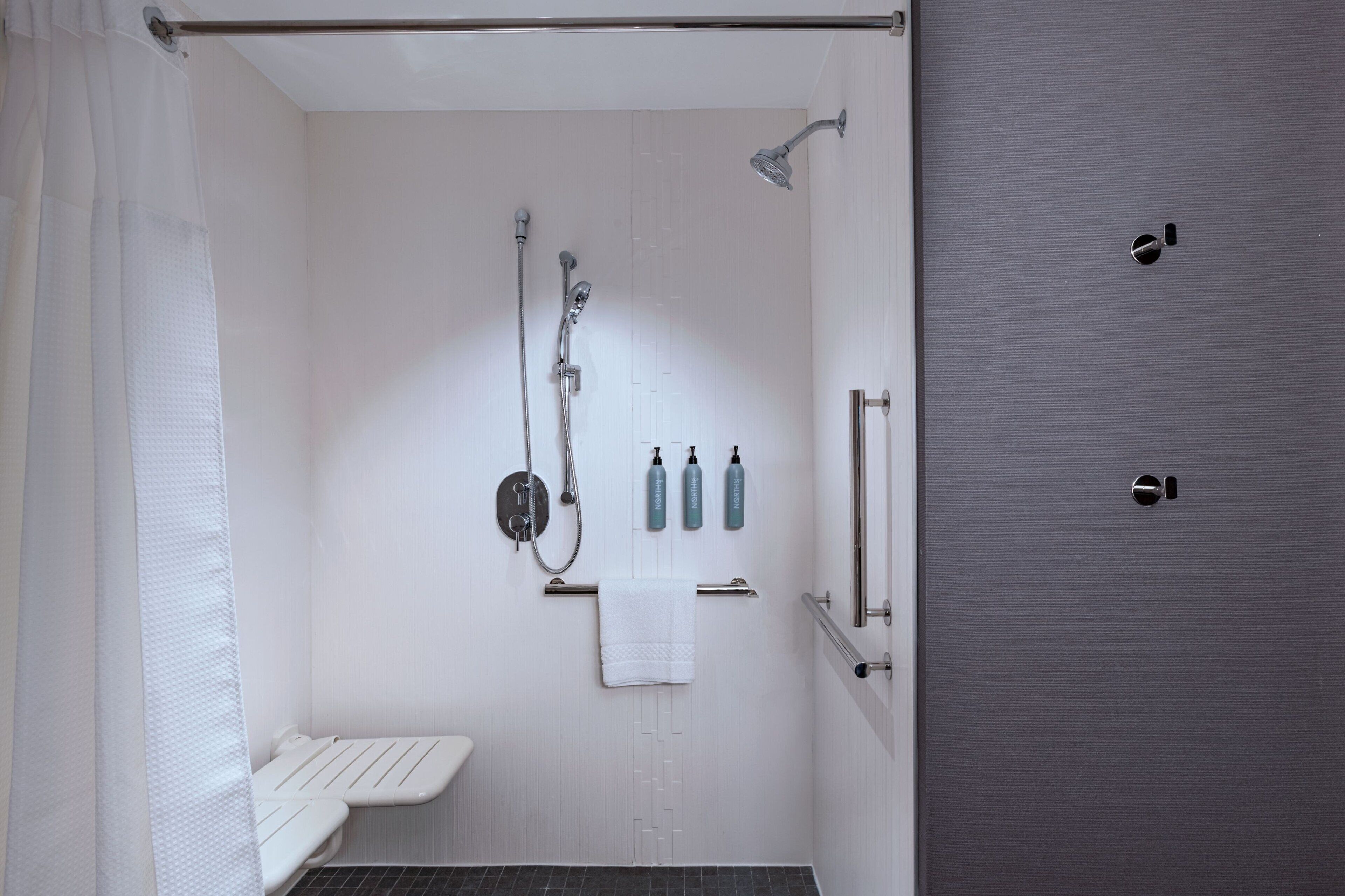 Un baño moderno con ducha, inodoro y barra para toallas.