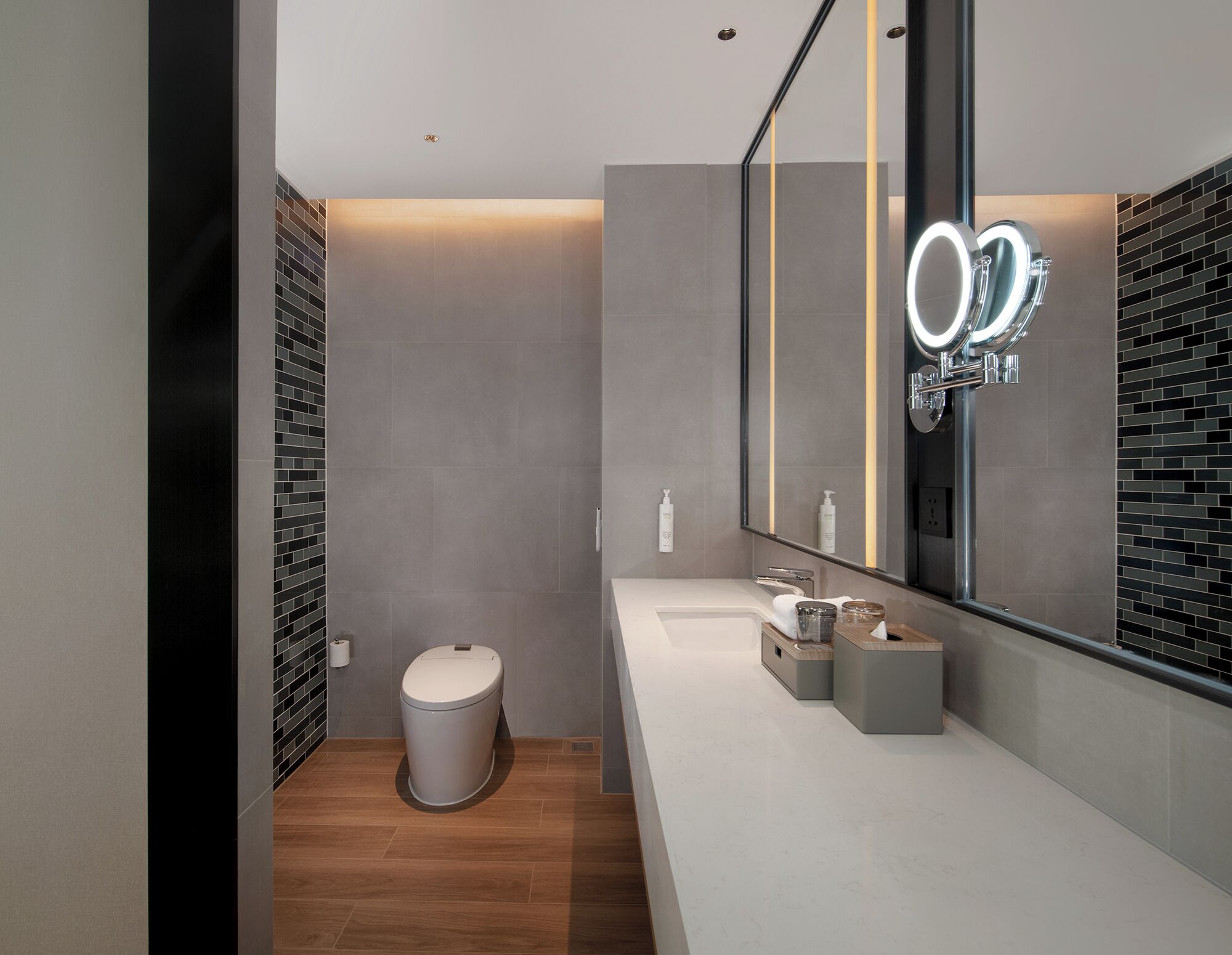 Un baño moderno con inodoro, lavamanos y espejo.