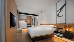 Una camera d'albergo moderna con un letto grande, un comodino e una televisione a schermo piatto fissata al muro.