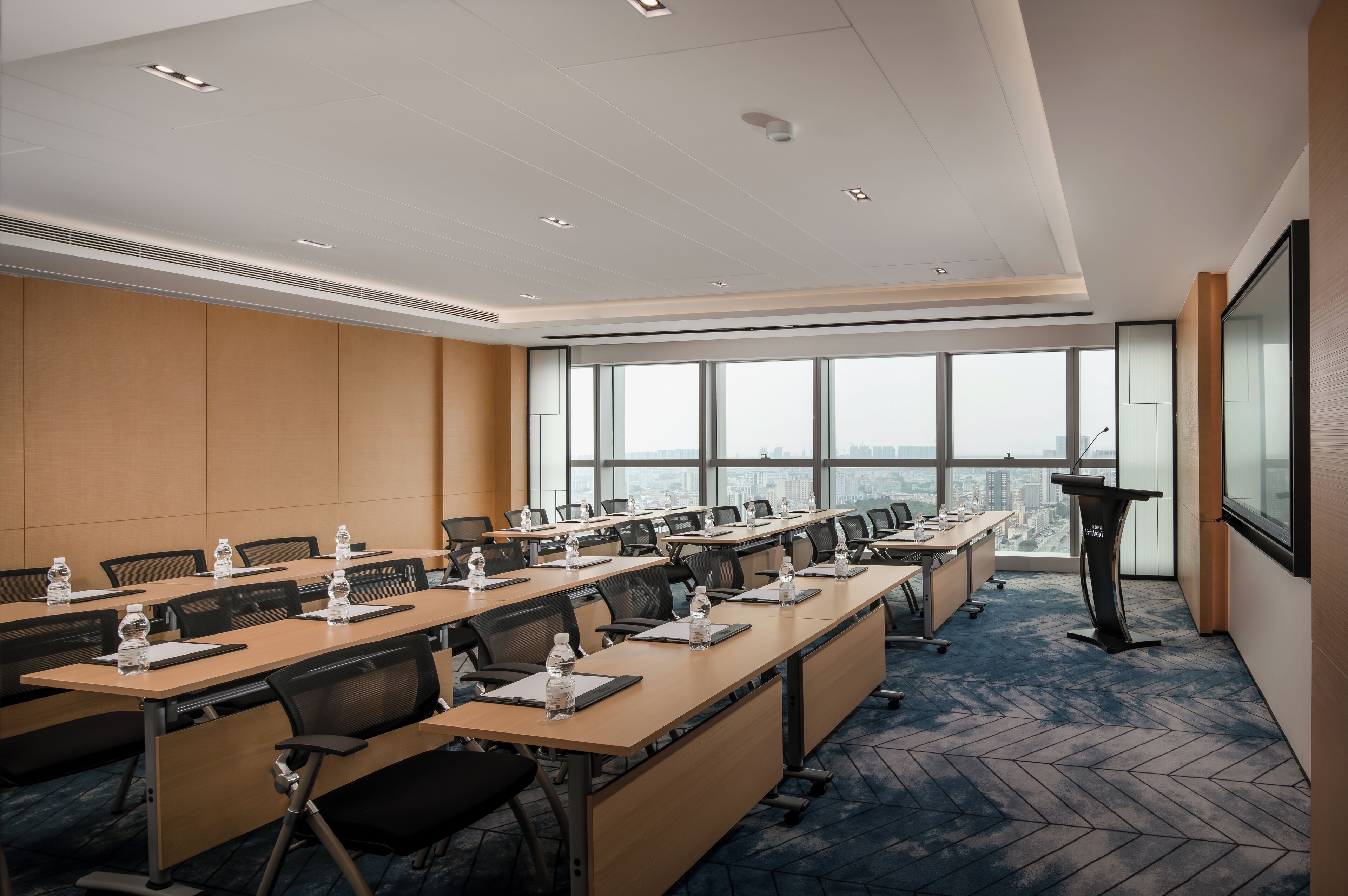 A conference room with long tables, chairs, water bottles, and a podium.