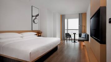 Une chambre d’hôtel moderne équipée d’un grand lit, d’un téléviseur à écran plat, d’une petite table et d’une chaise.