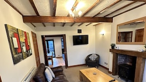 A living room with a brown leather sofa, a wooden coffee table, and a fireplace. - Lovely 3-bed House in Holmfirth (Holmfirth)