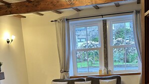 A cozy living room with a wooden coffee table, a brown leather sofa, and a window with curtains. - Lovely 3-bed House in Holmfirth (Holmfirth)
