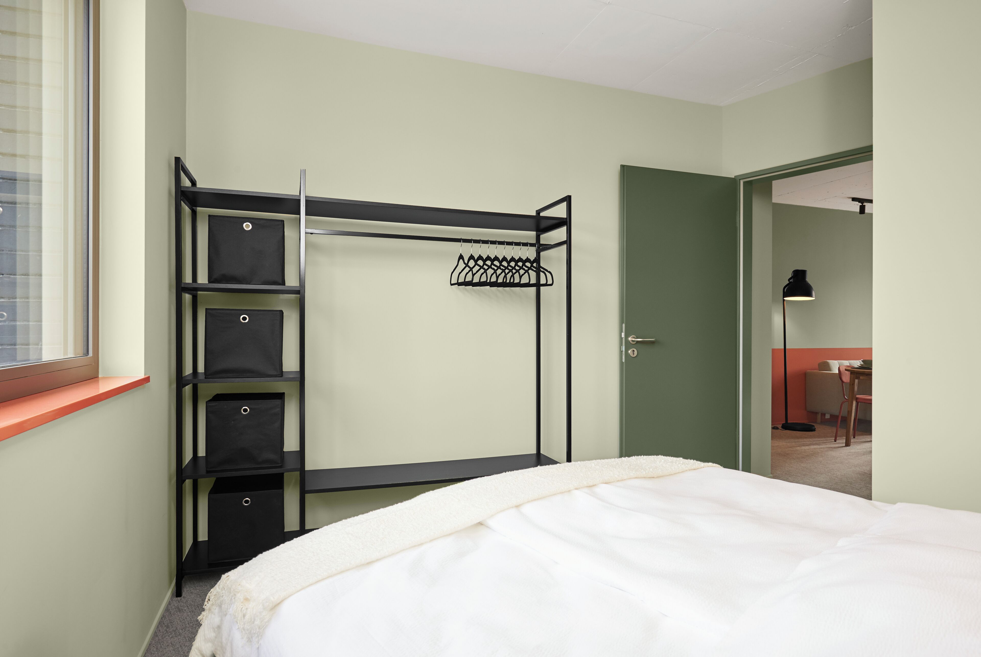 Une chambre à coucher comprenant un lit, une armoire intégrée avec des étagères et une porte donnant accès à une salle de bain.