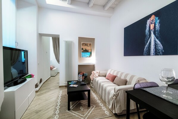 Una sala de estar moderna con televisor, sofá, mesa de centro y obras de arte.