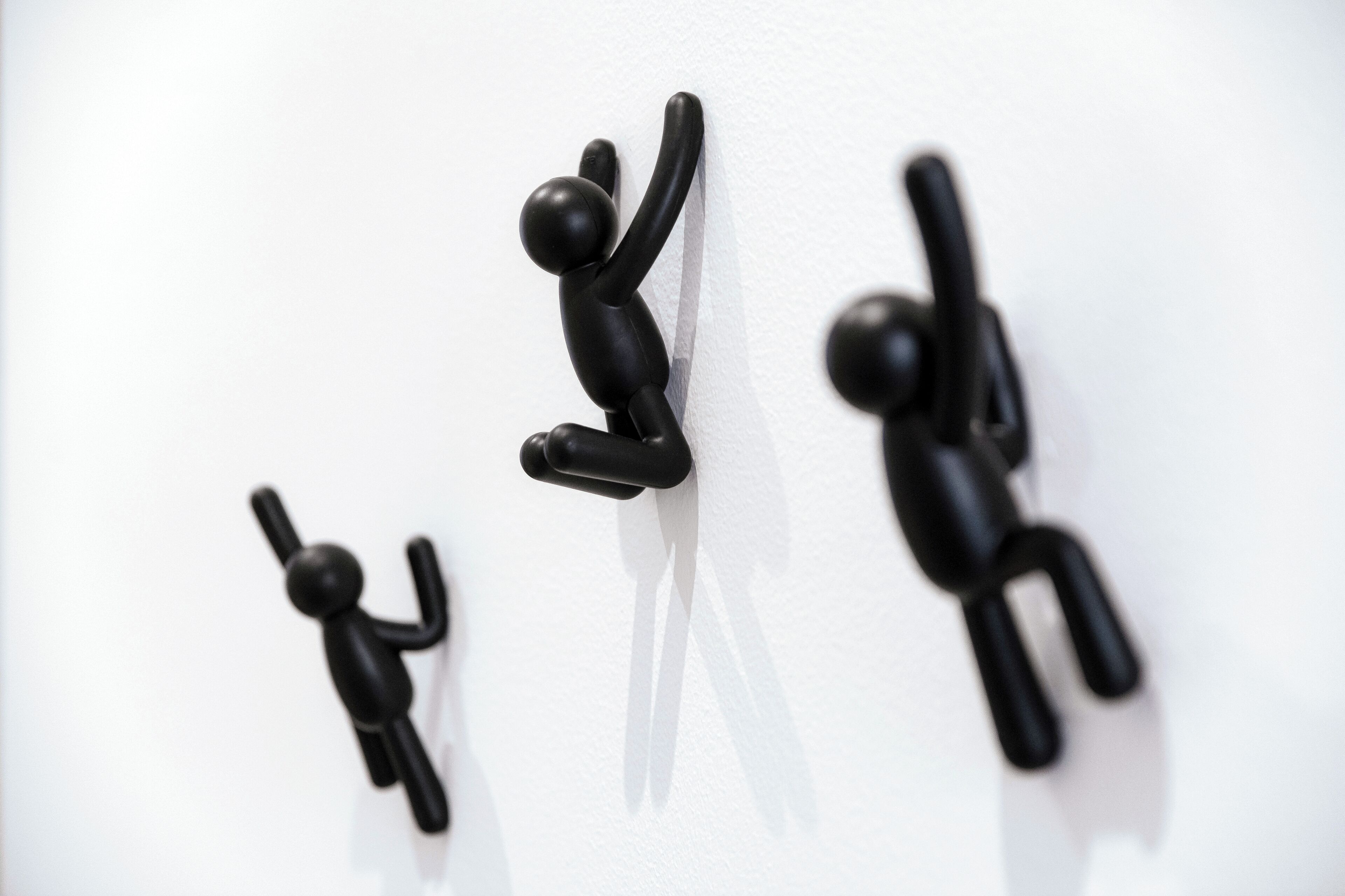 Three black wall-mounted figures in different climbing poses.