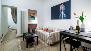 A living room with a sofa, a dining table, and a painting on the wall. - Lake Como Love (Como)
