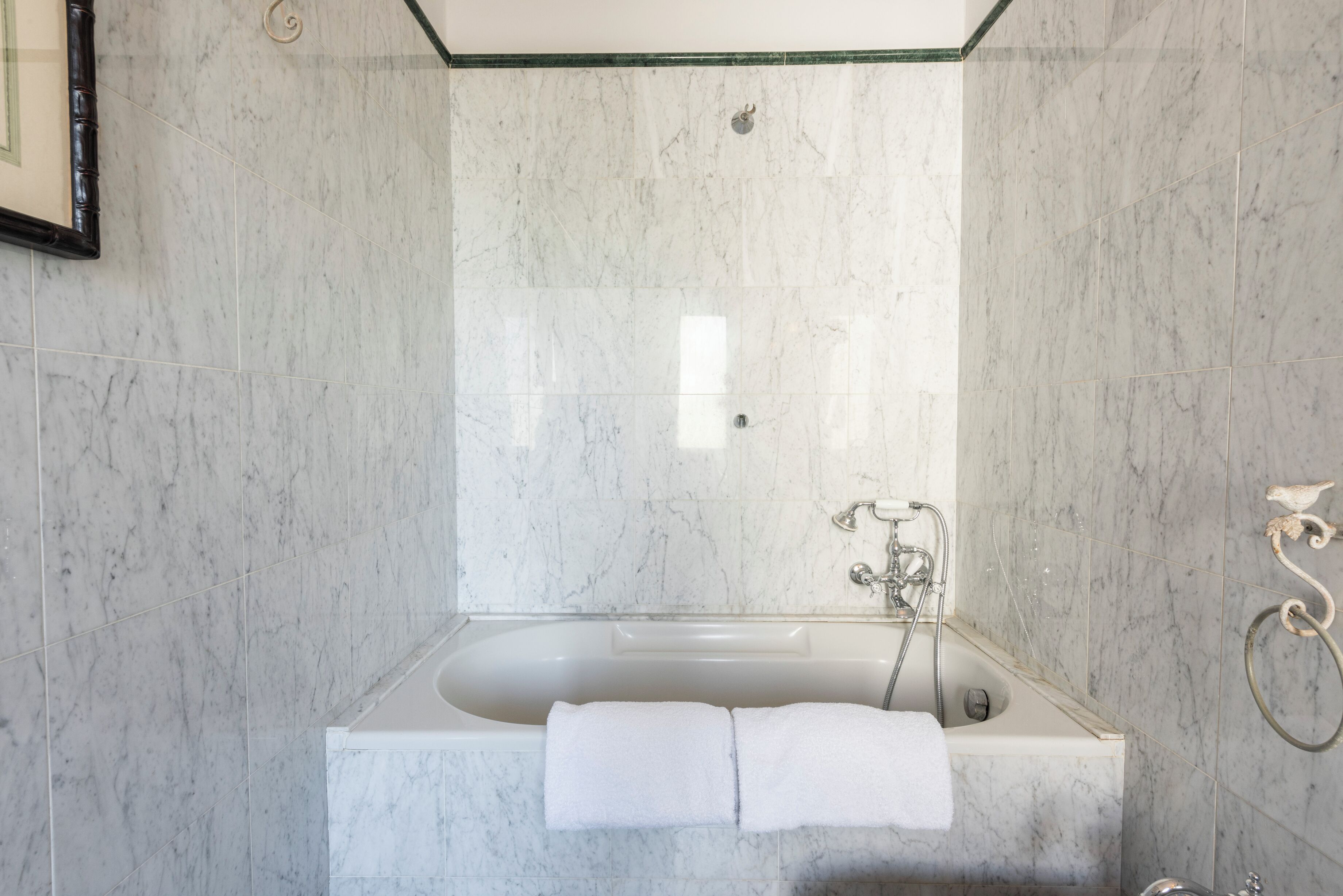 Une salle de bain moderne avec une baignoire sur pieds, des murs en marbre et un porte-serviettes.