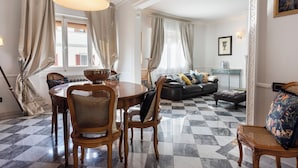 A dining area with a round table and chairs, a sofa, and a patterned rug. - Ippopotamo by Mmega (Florence)