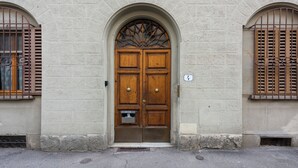 A building with a large wooden double door, a small window with a metal grill, and a number sign above the door. - Ippopotamo by Mmega (Florence)