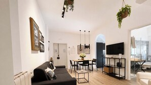 A modern living room with a sofa, dining table, and TV. - Casa Foresta - Apartment in Sorrento Centre (Sant'Agnello di Sorrento)