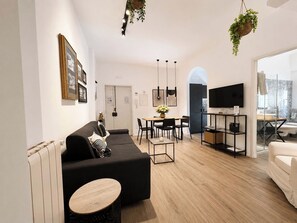A modern living room with a sofa, dining table, and TV.