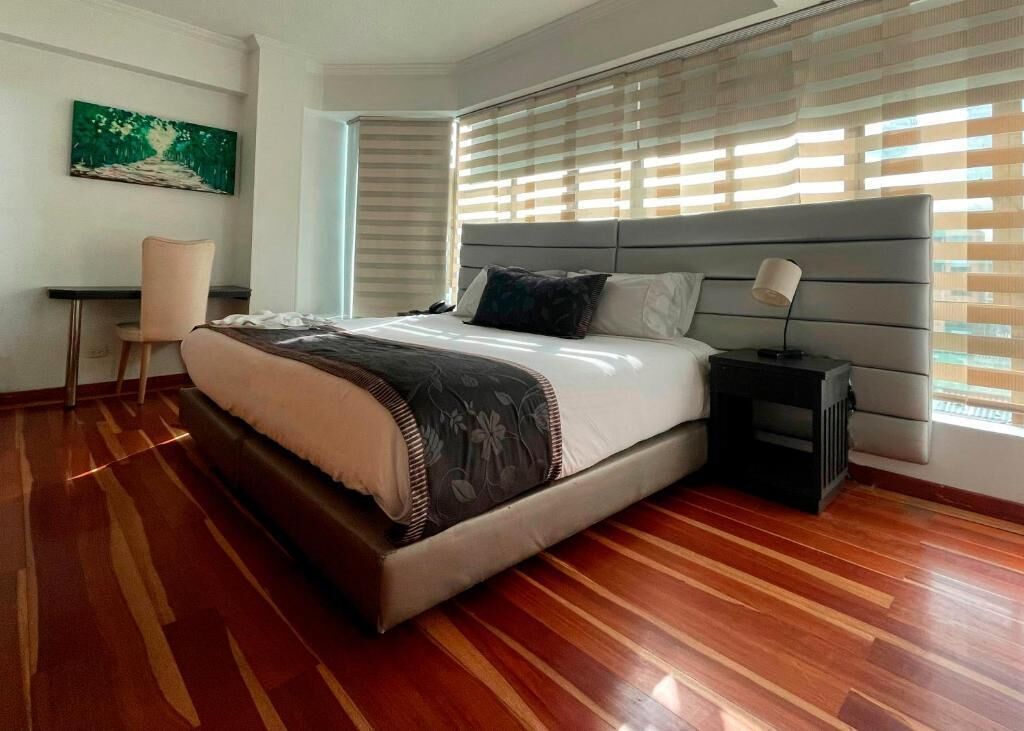 Una camera da letto con un letto grande, un comodino, una sedia e una finestra con tende.