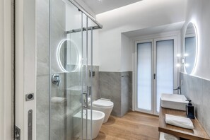 A modern bathroom with a glass shower enclosure, a toilet, a sink with a mirror, and a wooden vanity. - Nibla's Room Napoli (Naples)