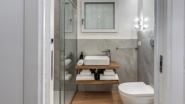A modern bathroom with a glass shower enclosure, a white sink with a marble countertop, and a wooden shelf with towels. - Nibla's Room Napoli (Naples)