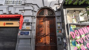 A wooden double door with a sign above it, a closed shutter to the left, and a shop window to the right. - Nibla's Room Napoli (Naples)