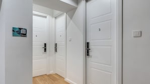 Un pasillo con puertas blancas, numeradas 5 y 3, y un cartel con un código QR en la pared.