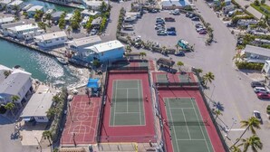 Oversigtsbillede af et kystområde med to tennisbaner, en parkeringsplads og en lysthavn.