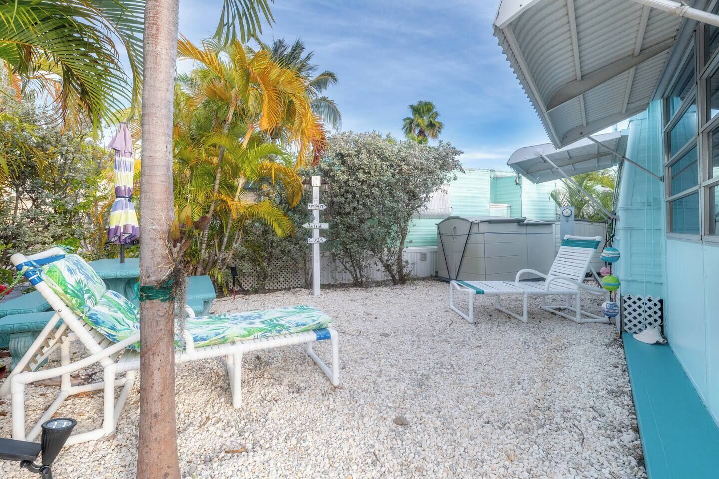 A covered outdoor area with two lounge chairs, a small pool, and a shed.