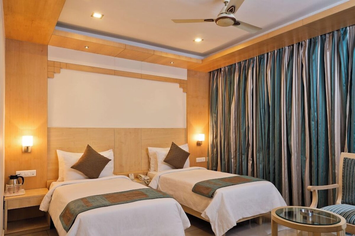 A hotel room with two beds, a ceiling fan, a nightstand with a phone, and a chair.