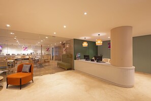 A modern hotel lobby with a reception desk, seating area, and a glass partition. - Z by Regenta Vijayawada (Vijayawada)