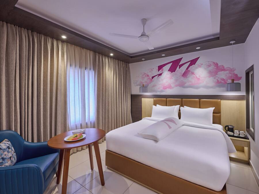Una habitación de hotel con cama, zona de estar, mesa y una pared decorativa.