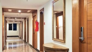 A hotel hallway with wooden doors, a fire extinguisher, and a large mirror. - Hotel Southern Grand (Vijayawada)
