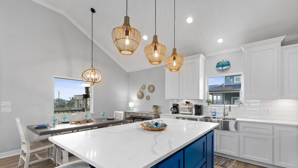 A modern kitchen with white cabinetry, a large island, and pendant lighting. - Steps to the Beach • Hot Tub • Modern 5★ Crystal Beach Getaway (Crystal Beach)