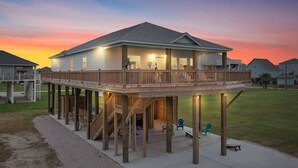 A two-story house with a wooden deck and a covered outdoor area. - Steps to the Beach • Hot Tub • Modern 5★ Crystal Beach Getaway (Crystal Beach)