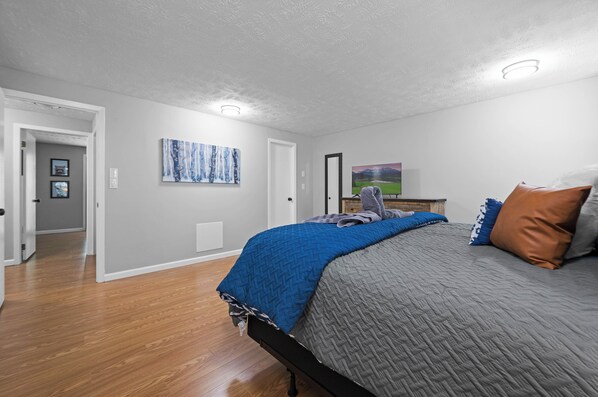 A bedroom with a bed, a painting, and a door. - NEW LISTING! Spacious Cabin with 3 beds, 3 baths, and 3 balconies w/Great Views! (Sevierville)