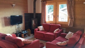 A cozy living room with a fireplace, red sofas, and a television.