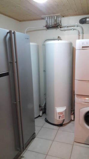 A compact kitchen with a refrigerator, a water heater, and a washing machine.