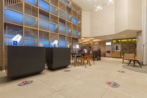 A hotel lobby with a reception desk, seating area, and a decorative wall with geometric patterns. - Vossa Bossa Flat Jardins (São Paulo)