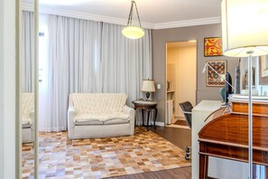 Una sala de estar con piso de cuadros, un sofá, una lámpara y un aparador de madera.