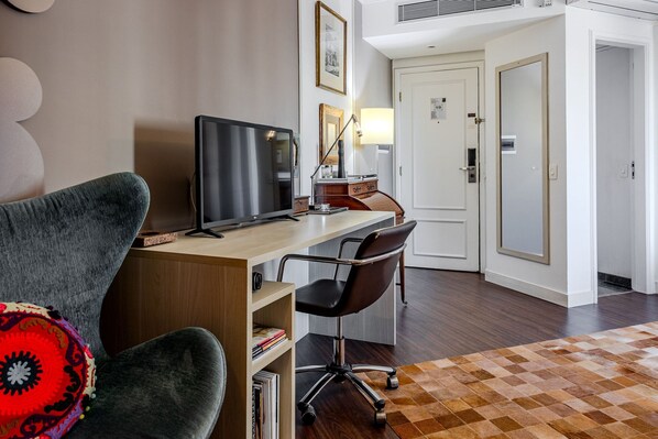 Une chambre d’hôtel équipée d’un bureau, d’un ordinateur, d’une chaise et d’un tapis à motifs.