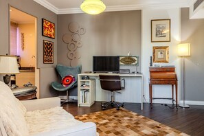 A modern living room with a sofa, a desk with a computer, a chair, and a lamp. - Vossa Bossa Flat Jardins (São Paulo)