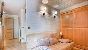 A room with a beige sofa, a red rug, and wooden paneling on the walls. - 2nd floor, balcony, tv, ski locker, 40m², Les Gets (Les Gets)