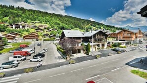 A mountain resort with wooden buildings, a main road, and a parking area. - 2nd floor, balcony, tv, ski locker, 40m², Les Gets (Les Gets)