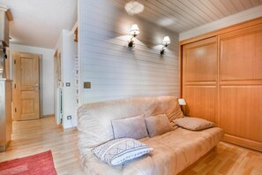 A room with a beige sofa, a red rug, and wooden paneling on the walls.
