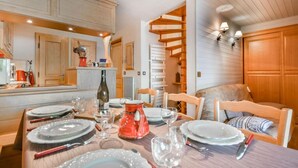 A dining area with a wooden table set for four, surrounded by wooden chairs. A spiral staircase is visible in the background, leading to an upper level. - 2nd floor, balcony, tv, ski locker, 40m², Les Gets (Les Gets)