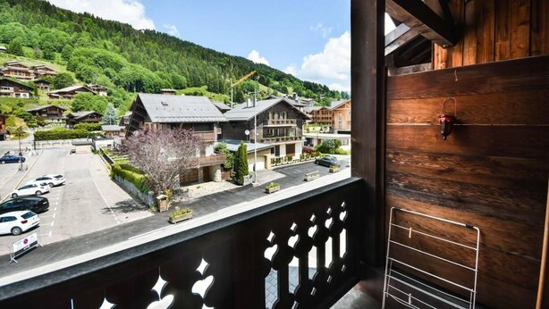 A balcony with a view of a mountain village, wooden buildings, and parked cars. - 2nd floor, balcony, tv, ski locker, 40m², Les Gets (Les Gets)