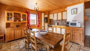 Una cocina tipo cabaña de madera con una mesa y sillas de madera, armarios y un microondas.