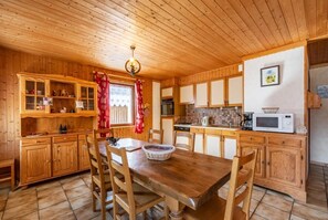 A wooden cabin-style kitchen with a wooden table and chairs, cabinets, and a microwave.