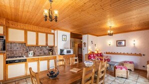 Cocina con paneles de madera, una mesa y sillas, microondas y hervidor.