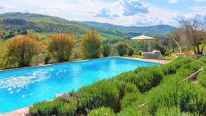 Une piscine offrant une vue sur des collines verdoyantes et un ciel dégagé.