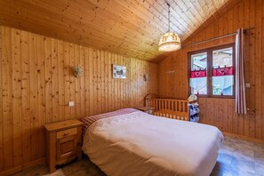 A wooden-paneled bedroom with a bed, nightstands, a window with curtains, and a view of the outside.