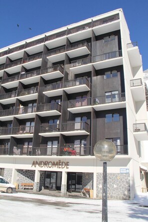 Um hotel de vários andares com design arquitetônico moderno, com varandas em cada andar e fachada de pedra.